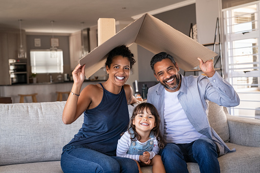 Feliz familia multiétnica con niño sosteniendo techo de cartón photo