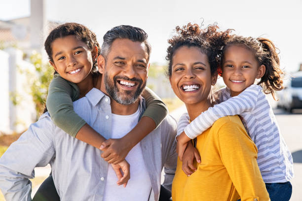 子供たちにピギーバックに乗る多民族の親 - men laughing african descent color image ストックフォトと画像