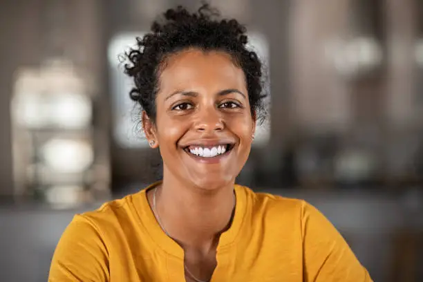 Portrait of a beautiful mid adult woman smiling at home. MIddle aged african woman in casual looking at camera with copy space. Cheerful mixed race girl relaxing at home with big laugh.