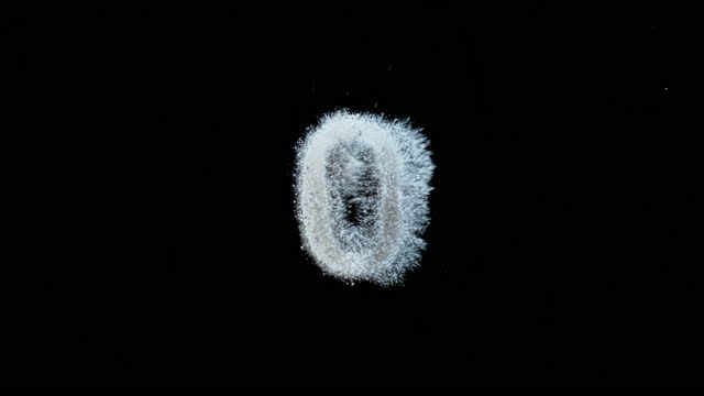 SLO MO LD White dust falling onto a black surface forming the number 