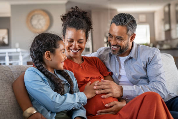 father and daughter touching baby bump of pregnant woman - abdomen women loving human hand imagens e fotografias de stock