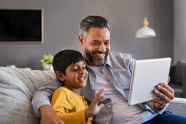 Photo of Father and son using digital tablet to make a video call