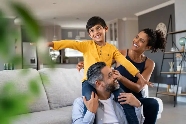 Photo of Happy son playing with ethnic parents