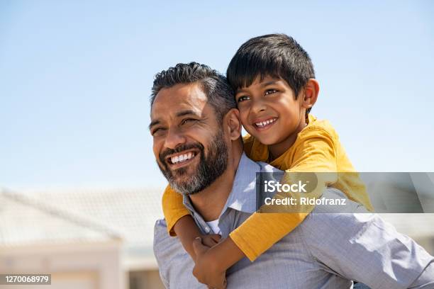 Happy Smiling Indian Father Giving Son Ride On Back Stock Photo - Download Image Now