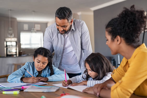 padres de raza mixta que ayudan a los niños en la tarea en casa - educación en el hogar fotografías e imágenes de stock