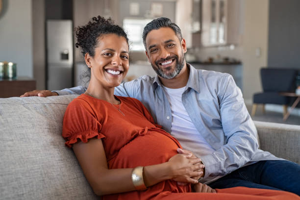 pregnant african woman with husband at home - human pregnancy prenatal care women abdomen imagens e fotografias de stock