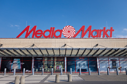 Amberg, Germany - August 9, 2020: Media Markt store in Amberg, Bavaria, Germany, Europe. Media Markt is a german chain, selling consumer electronics, with headquarter in Ingolstadt. It belongs to the Media-Saturn holding. Logo on the building and advertising on the facade. Sunny summer day with blue sky.