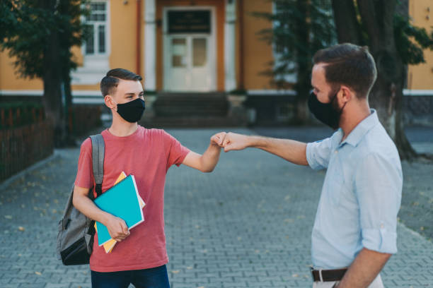 父は放課後拳バンプで息子に挨拶 - greeting teenager handshake men ストックフォトと画像