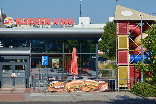 Amberg, Germany - August 12, 2020: Restaurant of the fast food chain Burgerking in the german town Amberg. Burger King has its headquarter in Florida. Logo and advertising on the building. Parking lot in the foreground.