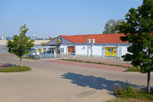 Amberg, Germany - August 9, 2020: Store of the Lidl supermarket chain in the german town Amberg. Lidl has its headquarter in Neckarsulm, Germany with over 10000 stores in Europe. Logo and advertising on the building. Parking lot in the foreground.