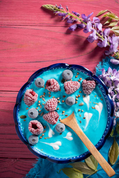 Blue spirulina yogurt bowl breakfast with berries on pink table