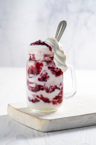 Raspberries yogurt smoothie overflow on a white cutting board table
