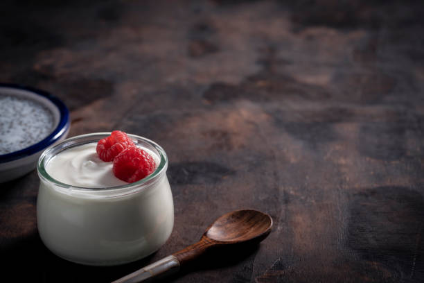 istock Yogurt jar with rapsberries in moody low key dark wood 1270075309