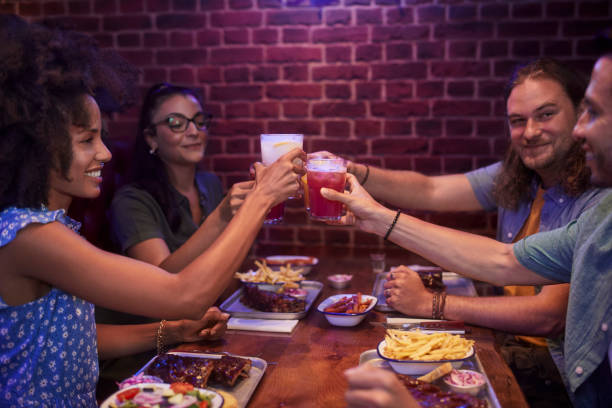 istock Friends making a toast with colorful drinks and having bbq ribs in retro restaurant 1270079294