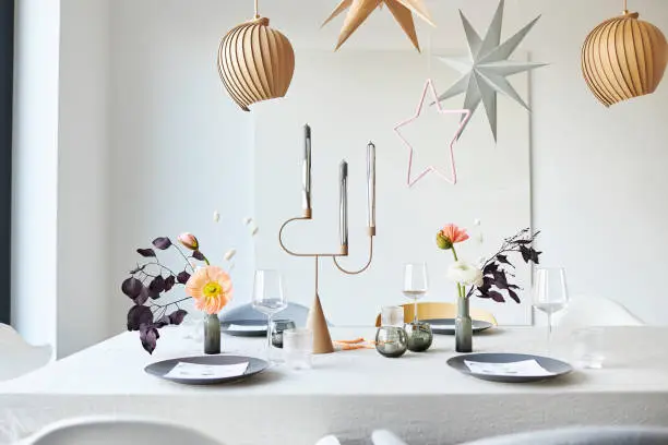 a modern and simply designed Christmas table decoration with advent wreath, stars and flowers photographed in high resolution in color in a bright apartment