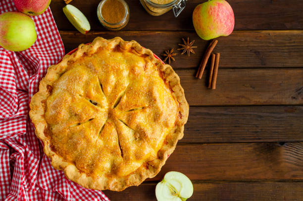 Classic American apple pie with cinnamon on a dark wooden background. Rustic style. Top view, copy space. Classic American apple pie with cinnamon on a dark wooden background. Rustic style. Top view, copy space apple pie photos stock pictures, royalty-free photos & images