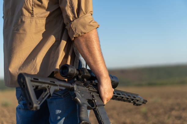 un rifle en la mano de un hombre, de cerca. cazador con un arma en la caza en el fondo de un hermoso paisaje de verano - armed forces human hand rifle bullet fotografías e imágenes de stock