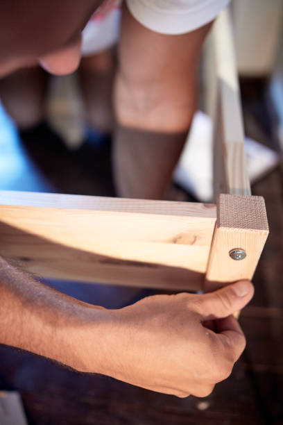 istock Carpenter hobbyist assembling wooden boards at home / garage. 1270088843
