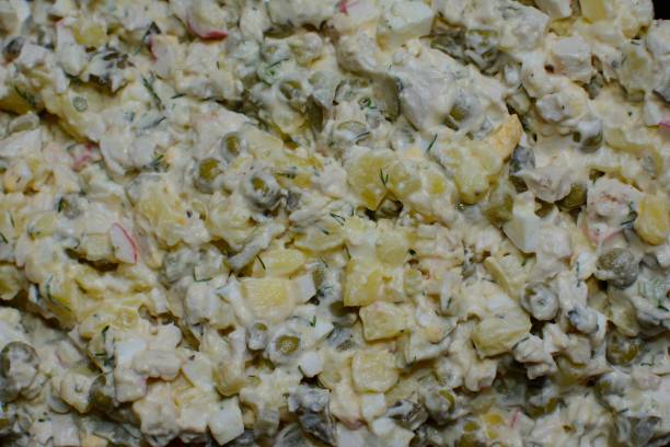 istock salad with sauce, potatoes, peas, dill, cucumbers, eggs. Close-up, top view 1270089276