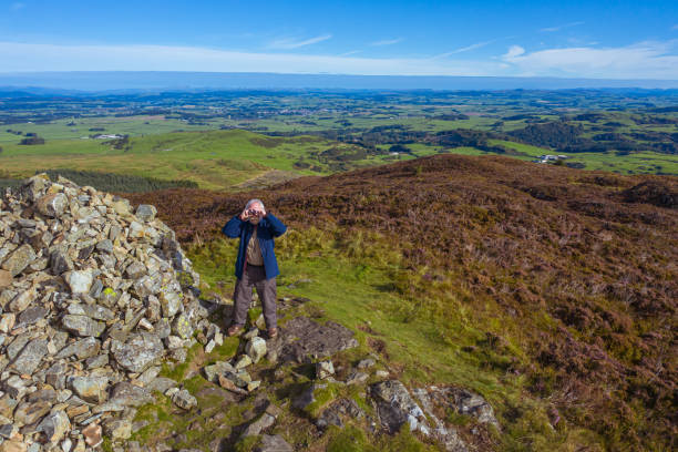 istock High angle view of a senior man using binoculars while standing next to a cairn on a Scottish hilltop 1270091406