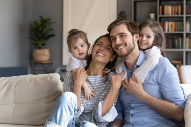 笑顔の両親を抱きしめる愛する小さな女の子。 - apartment television family couple ストックフォトと画像