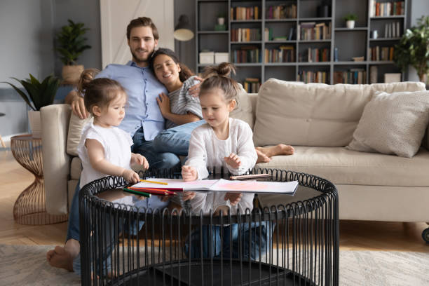 istock Happy loving young couple watching two small daughters drawing pictures. 1270093643