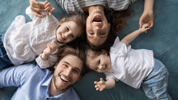 istock Happy young parents relaxing on bed with joyful little daughters. 1270093675