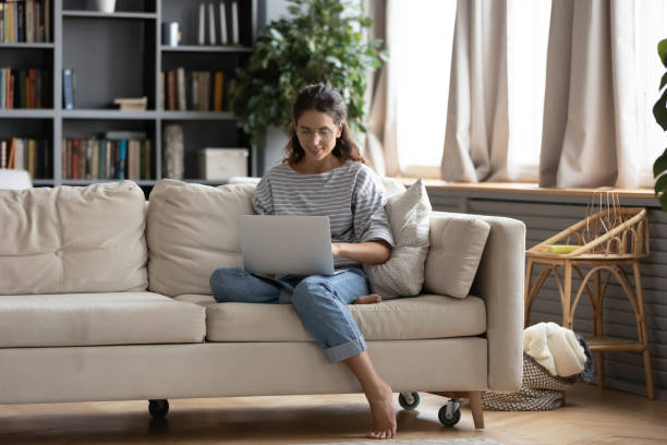 istock Smiling young attractive barefoot woman in eyeglasses using computer. 1270093686