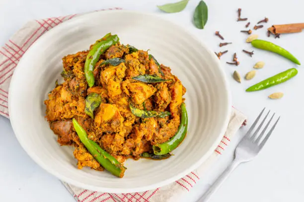 Indian Spiced Chicken Curry on White Background with Scattered Spices