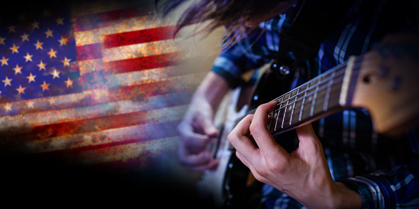 Hombre de guitarra eléctrica tocando en el fondo de la bandera de EE.UU. photo
