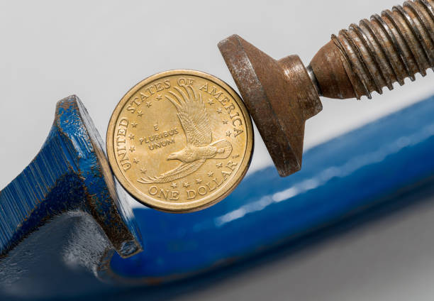 istock USA one dollar coin being squeezed between the solid jaws of a vise or vice 1270099702