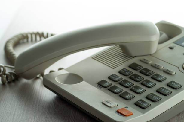 Desk phone on the desk with the handset off. Selective focus.