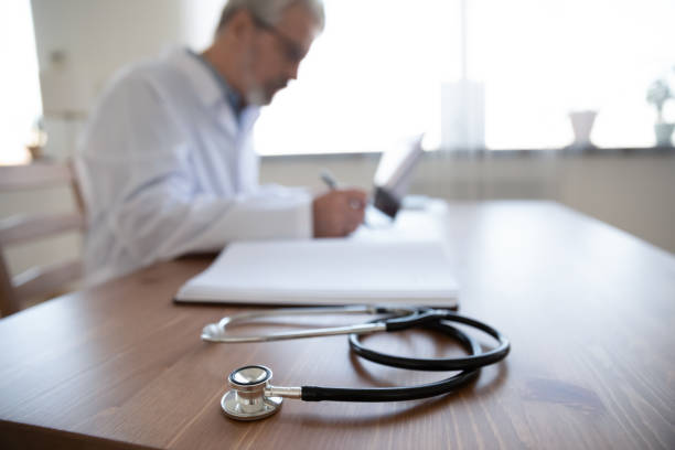 Close up senior mature doctor work desk with stethoscope