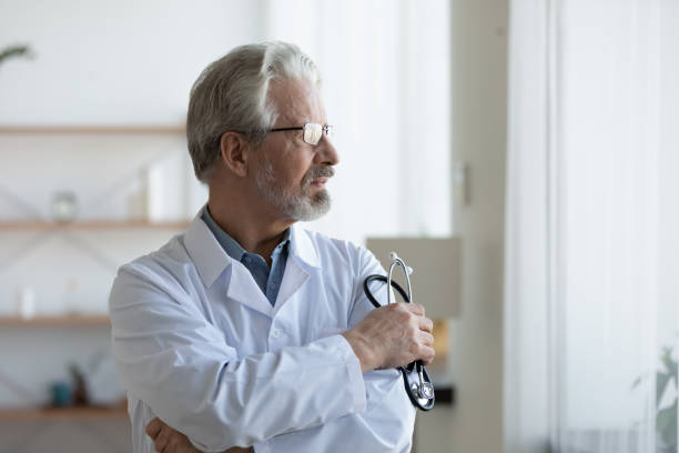 istock Thoughtful mature doctor wearing glasses and uniform lost in thoughts 1270104004