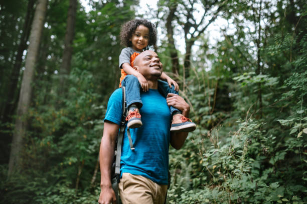 父は太平洋北西部の森の道をハイキングで息子を運ぶ - family walking parent lifestyles ストックフォトと画像