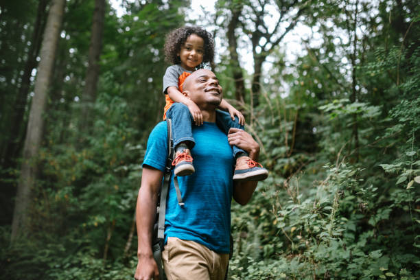 Father Carries Son On Hike Through Forest Trail in Pacific Northwest A young mixed race family spends time together outside in Washington state, enjoying the beauty of the woods in the PNW.  The dad holds his boy on his shoulders. happy family stock pictures, royalty-free photos & images
