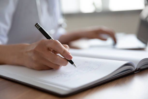 istock Close up female doctor filling documents and using laptop 1270104089