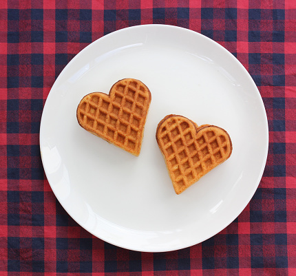 two waffles in the shape of a heart on a plate, top view. food, dessert, treats.