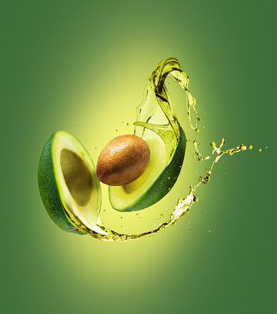Sliced avocado with splashes isolated on a green background
