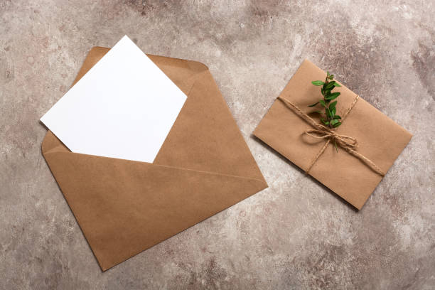 istock Blank paper card in brown envelope on beige textured background. Invitation cards template. Mockup for your design. Top view, flat lay. 1270104920