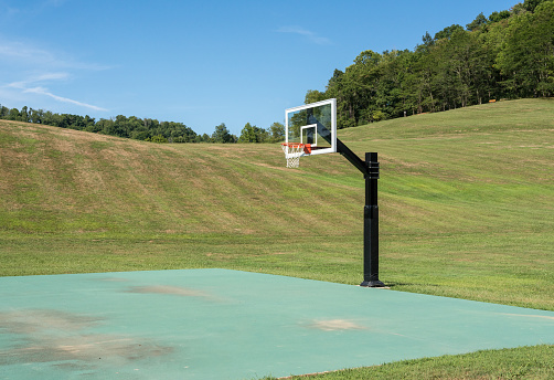 Empty court for basketball or netball in state park surrounded by hills and trees in the distance. No people.