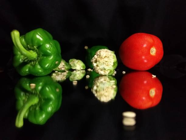 istock Green capsicum (shimla mirch) or bell pepper image with seed and stalk and tomato with black background 1270105931