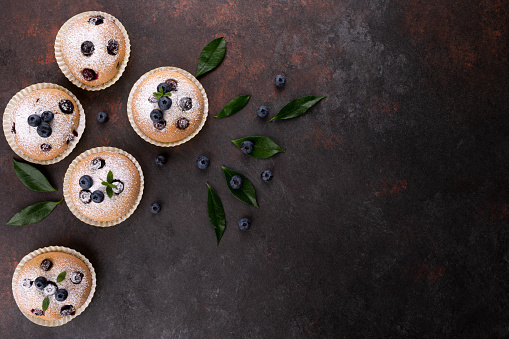 Blueberry muffins on brown wood background flat lay with copy space