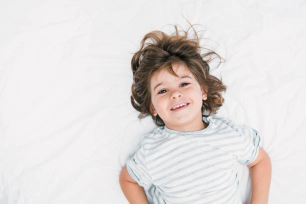 istock A smiling child looking at camera - lying on the bedroom bed with white background 1270108363