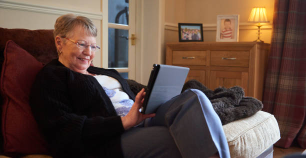 デジタルタブレットで読むシニア女性 - senior adult relaxation sofa reading ストックフォトと画像