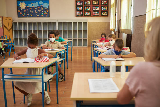 istock Group of elementary students with protective face masks in a classroom during coronavirus pandemic 1270121013