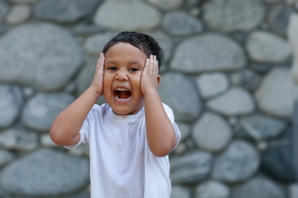 Young latino boy holding his head with both of his hands while laughing out loud expressing joy. stock photo