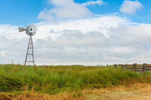 Modern power windmills  and old fashioned pump windmill in field, on Route 66 Texas, USA
