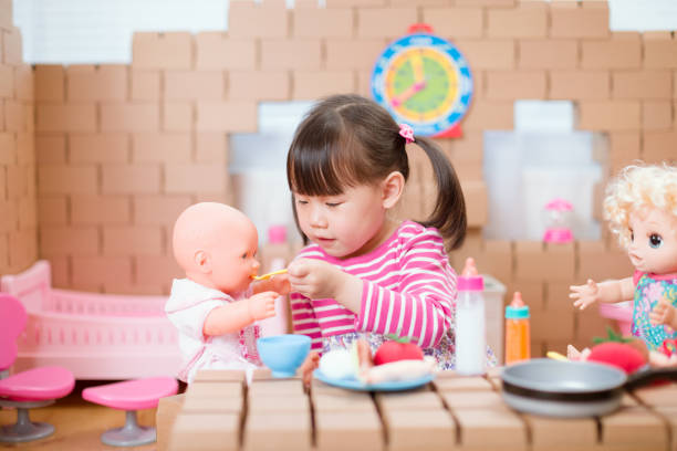 young girl pretends play babysitting with baby doll at home young girl pretends play babysitting with baby doll at home girl playing with doll stock pictures, royalty-free photos & images