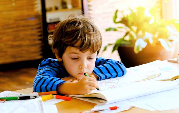 istock Little boy drawing and coloring at his classroom desk 1270129106